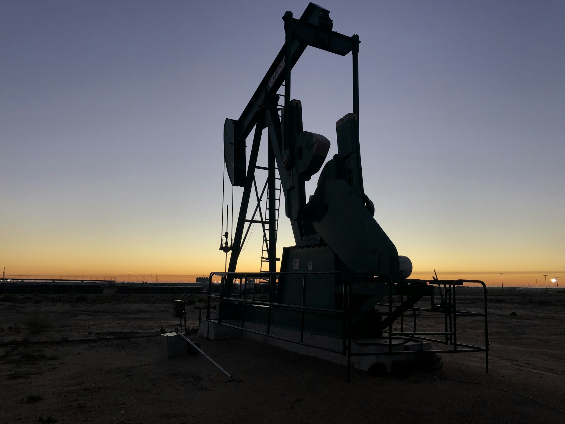 Pumpjack silhouetted against a golden dusk sky